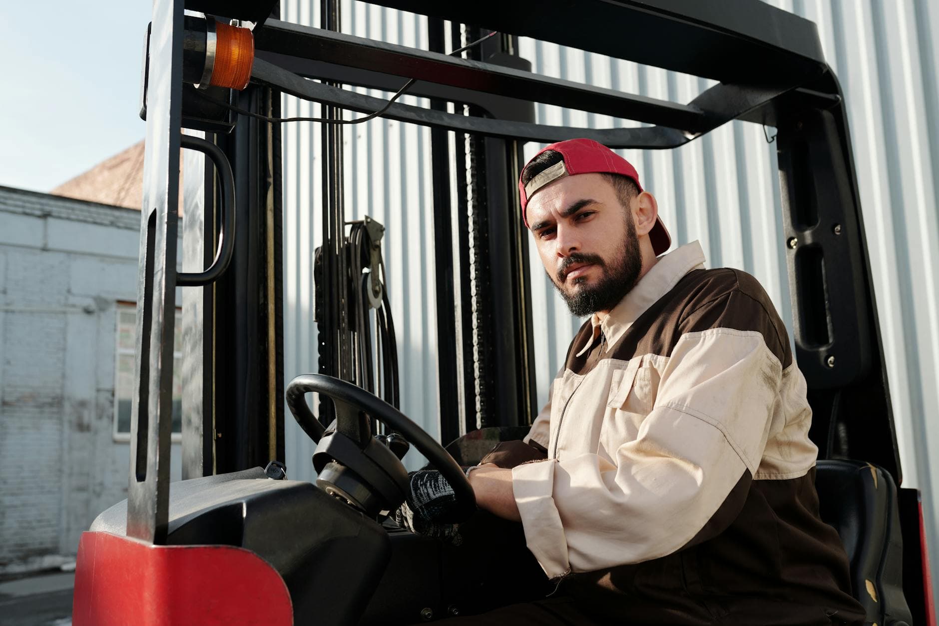 A lift-truck operator at the controls in an outdoor industrial yard.