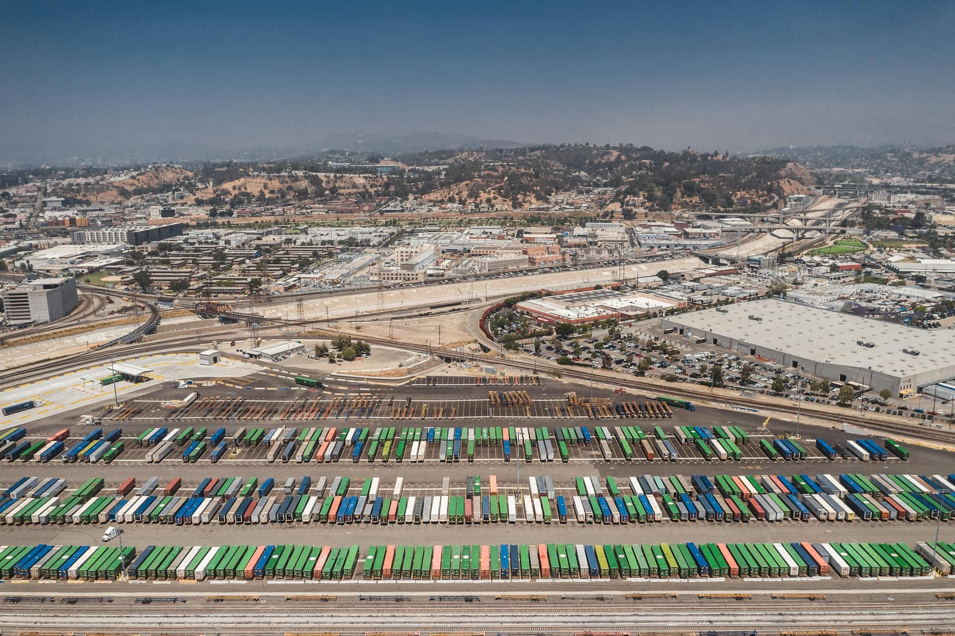Aerial view of colorful shipping containers stacked across a sprawling North American port terminal.