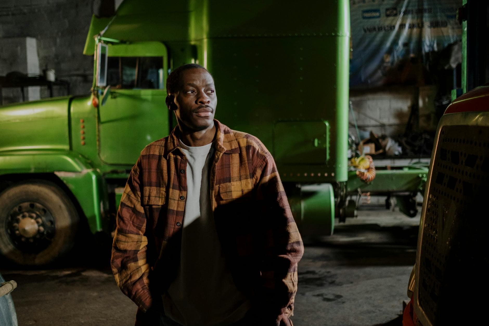 A truck driver standing beside the cab of a conventional tractor.