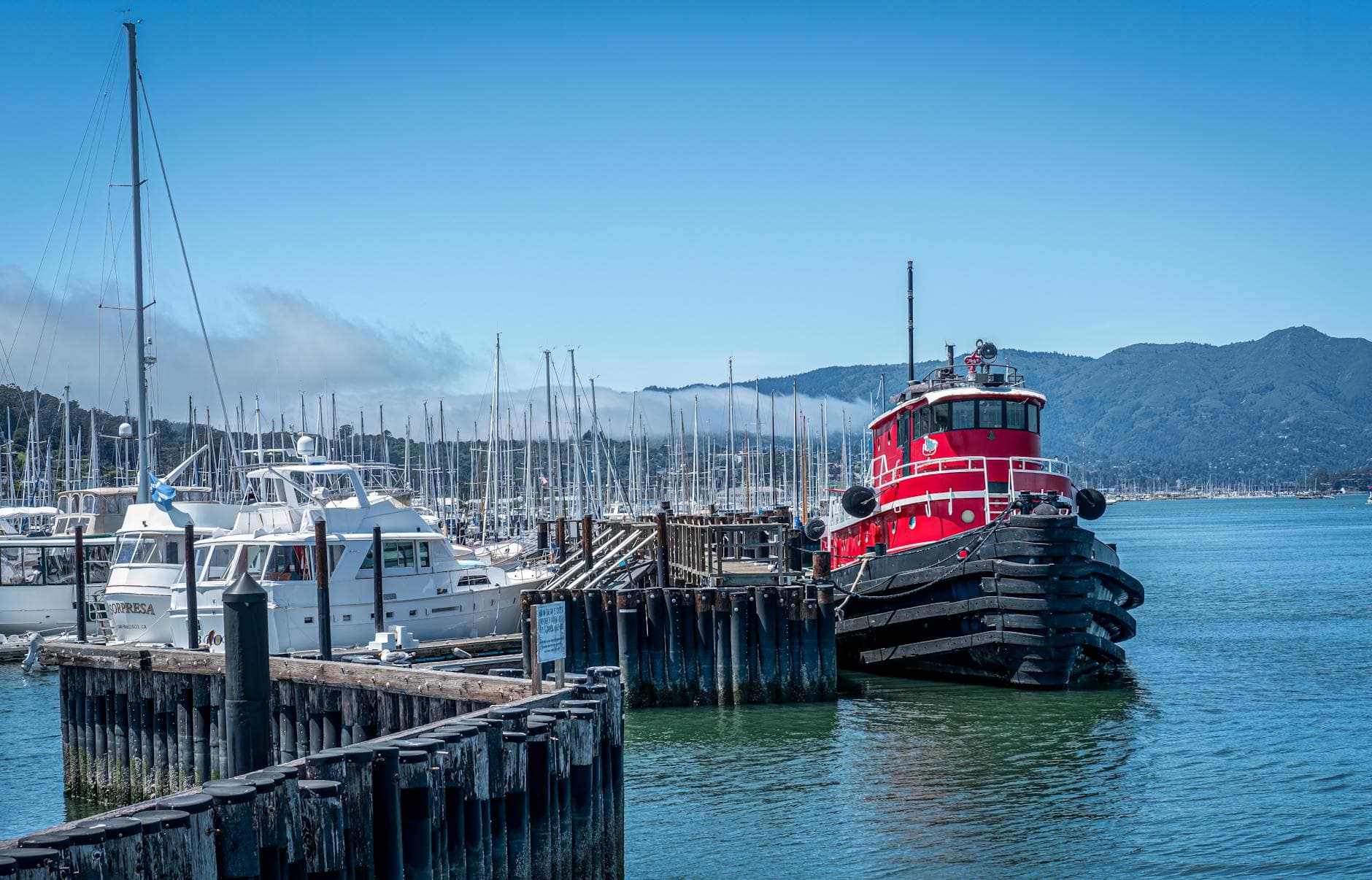 A red harbor tugboat moored at a marina on a clear day.
