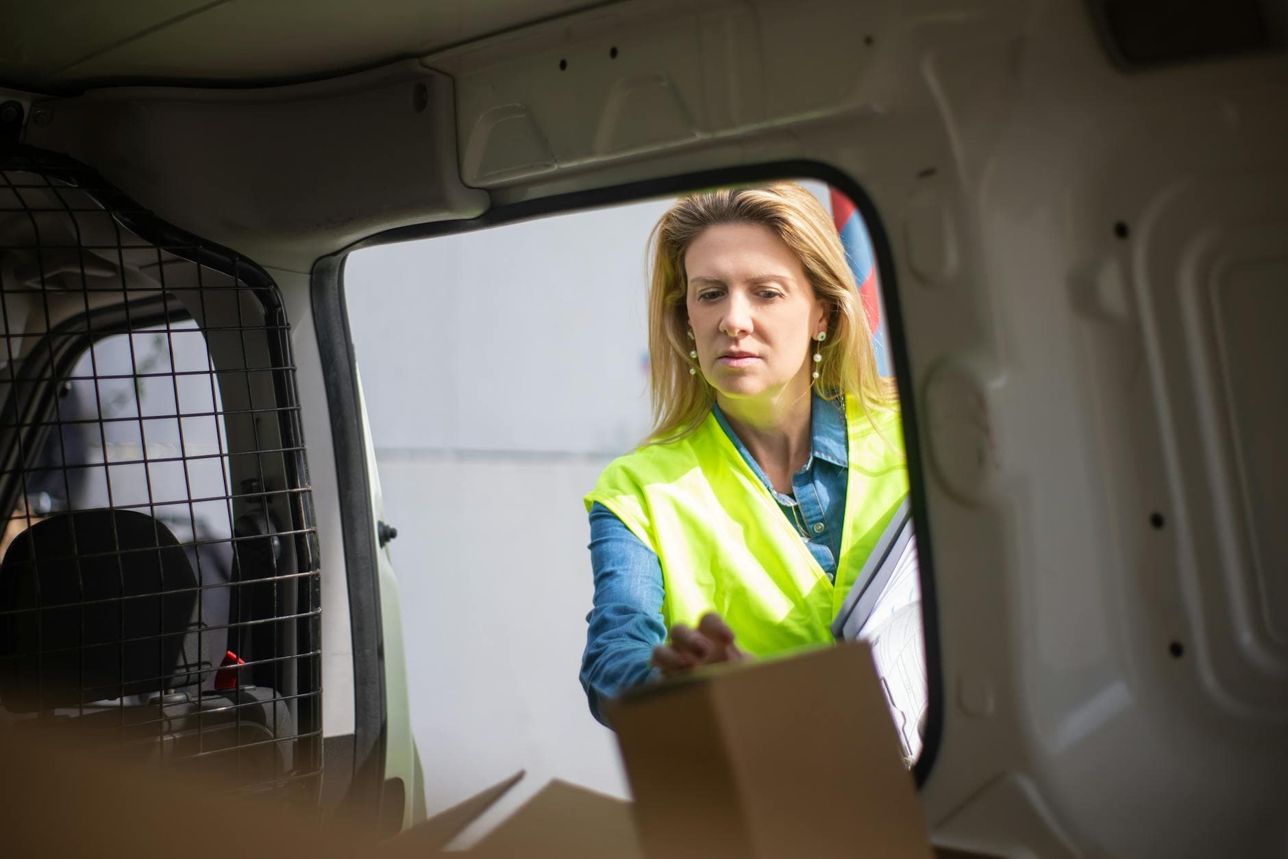 A worker in a high-visibility vest loading boxes into a delivery van.